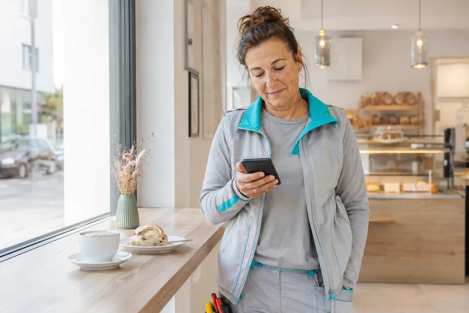Handwerkerin nutzt ihr Smartphone in einer Pause